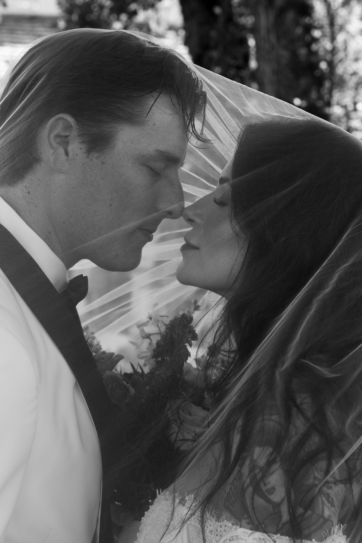 A couple sharing a kiss beneath the bridal veil