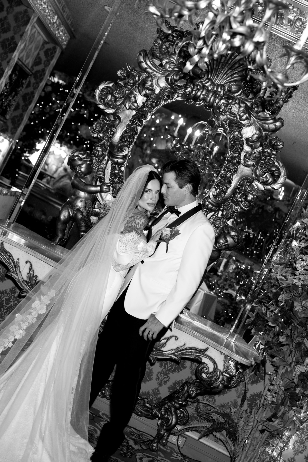 A black-and-white wedding portrait in an ornate mirror